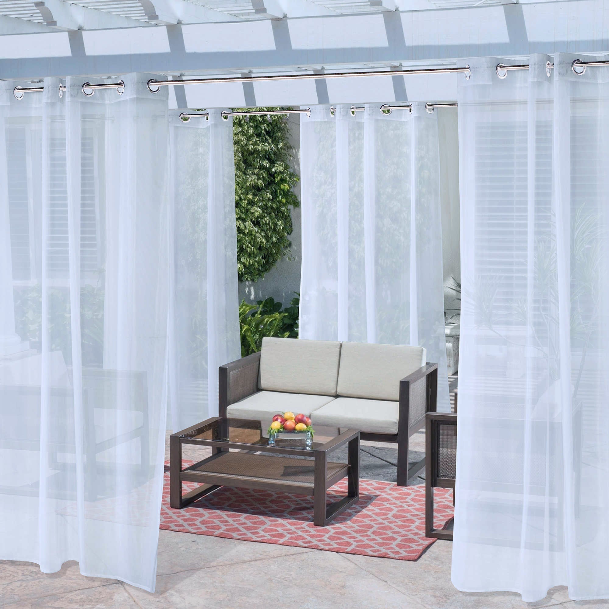 White grommet waterproof privacy outdoor sheer curtains transform a patio, hanging from a pergola over lounge furniture.