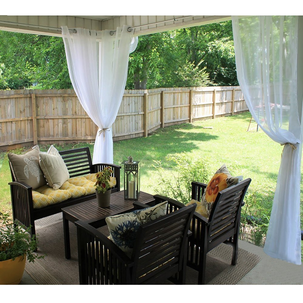 White grommet waterproof sheer outdoor privacy curtains tied back on a patio, defining a stylish private oasis with seating.